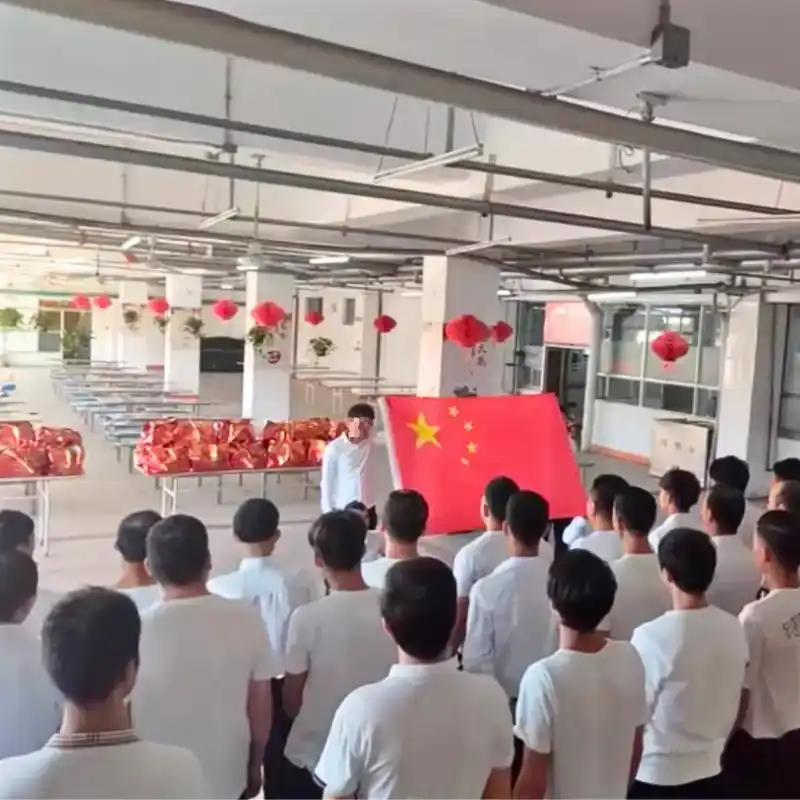 Workers assembly from another angle, showing the whole group and two people in front of them with the flag
